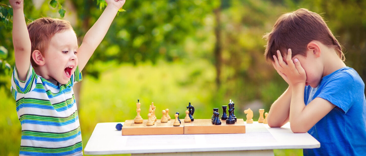 two boys playing chess, one has just won the game and is celebrating