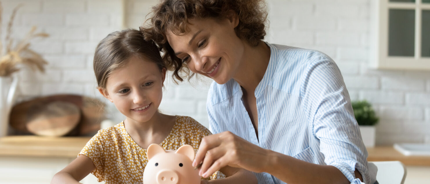 Mother and daughter saving in a piggy bank