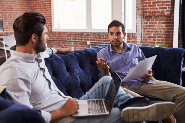 Two businessmen have an informal meeting on a sofa