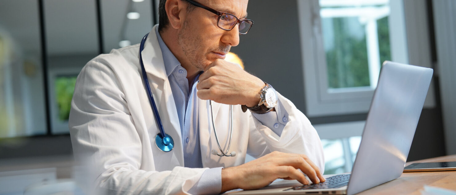 A doctor working at a laptop.