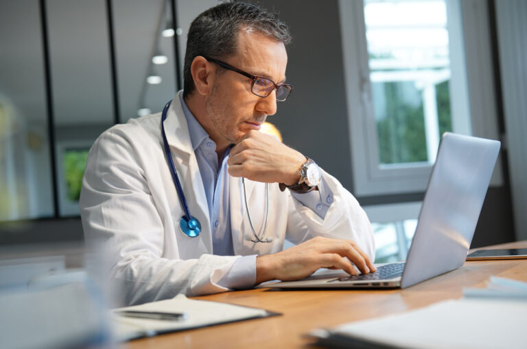 A doctor working at a laptop.