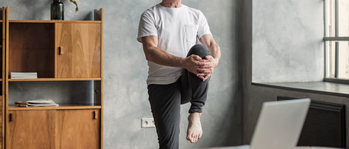 A man stretching while following a virtual exercise class.