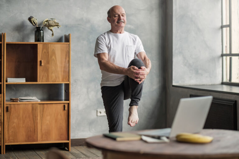 A man stretching while following a virtual exercise class.