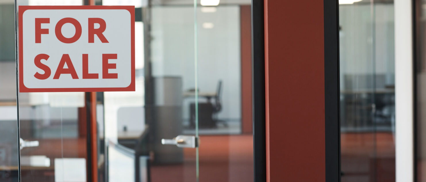 A “For Sale” sign hangs on the door of an empty office.