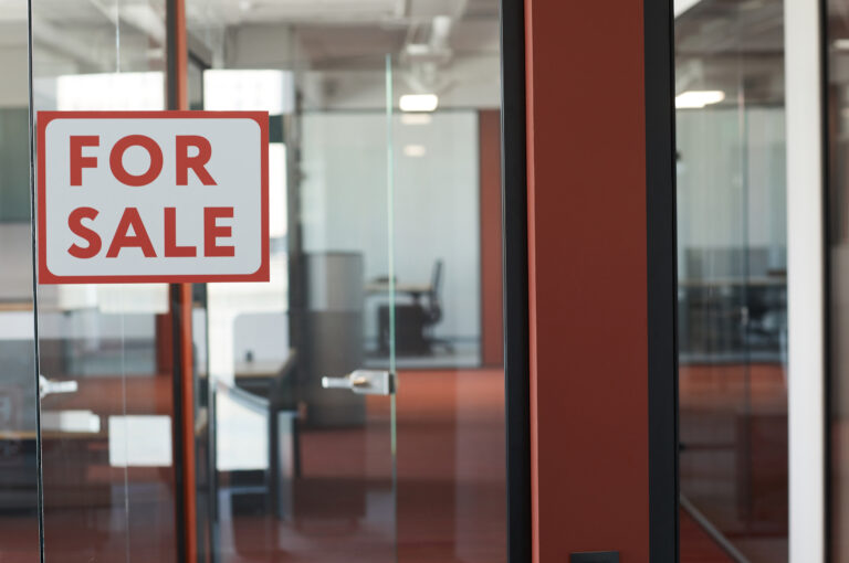 A “For Sale” sign hangs on the door of an empty office.