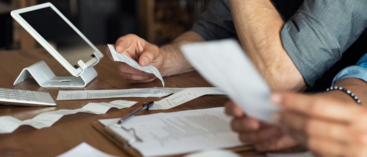 Two business owners review receipts at a table with an iPad.