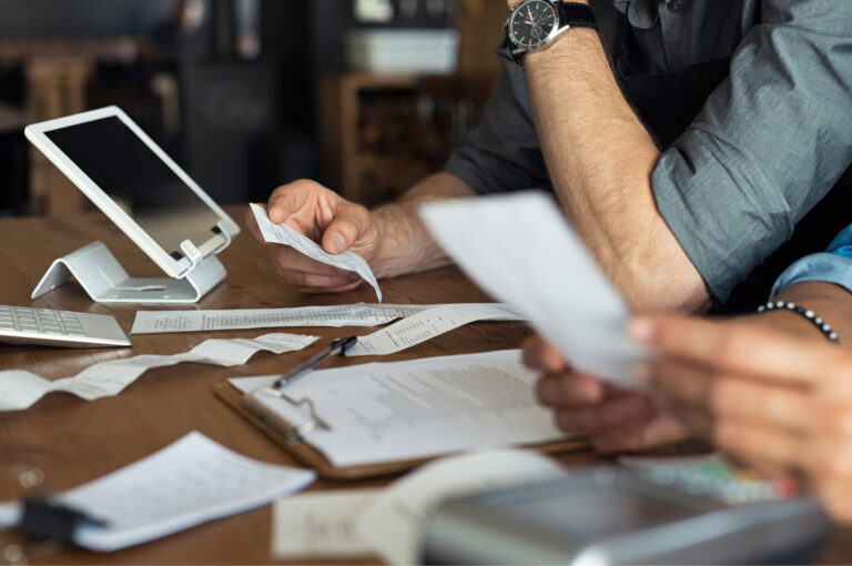 Two business owners review receipts at a table with an iPad.