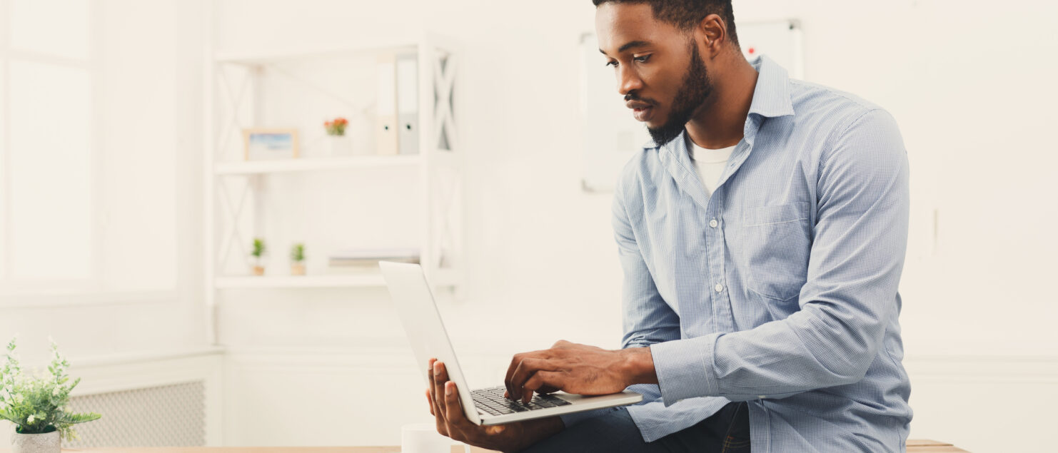 A business owner sits on his desk using his laptop.