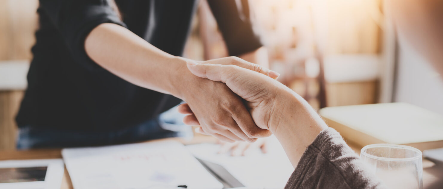 Two people shaking hands in an office.